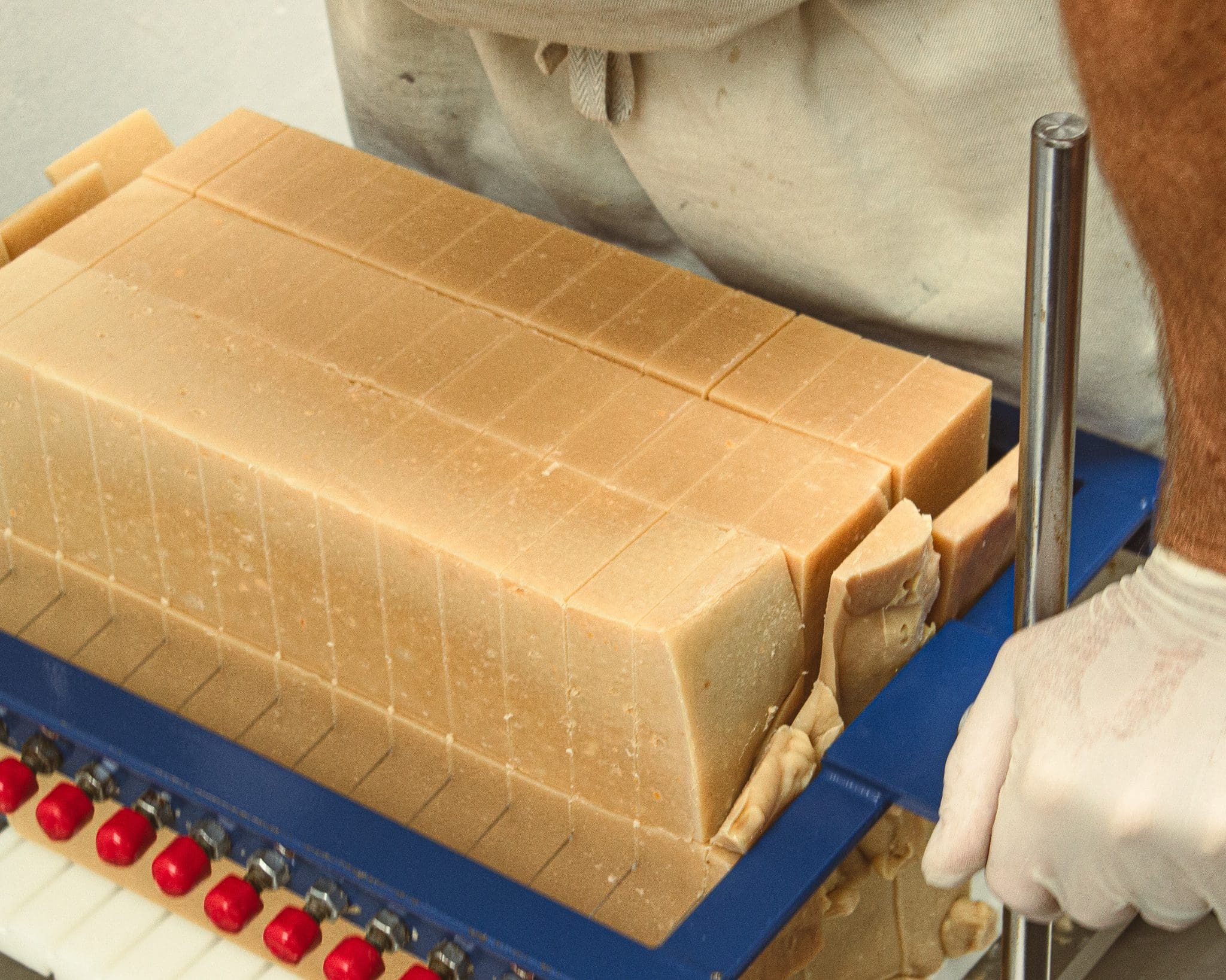 Man cutting through large block of soap to create smaller individual bars of soap