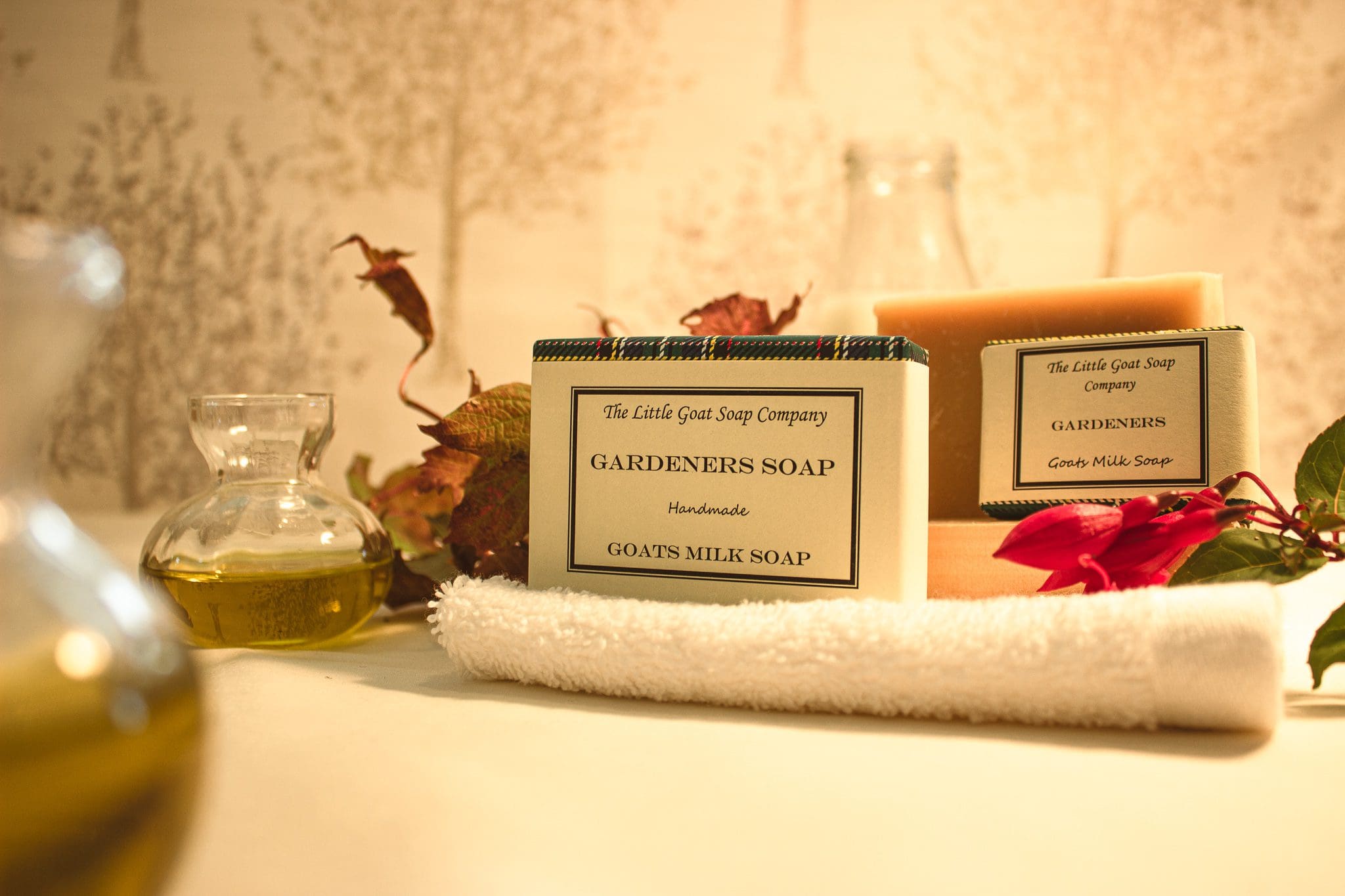 soap products from the little goat soap company showing their gardeners soap, the photo uses depth of field with items such as jars of oils, and autumnal leaves