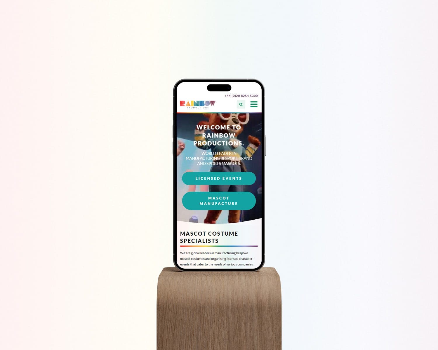 Rainbow Productions website shown on iphone on a wood plinth