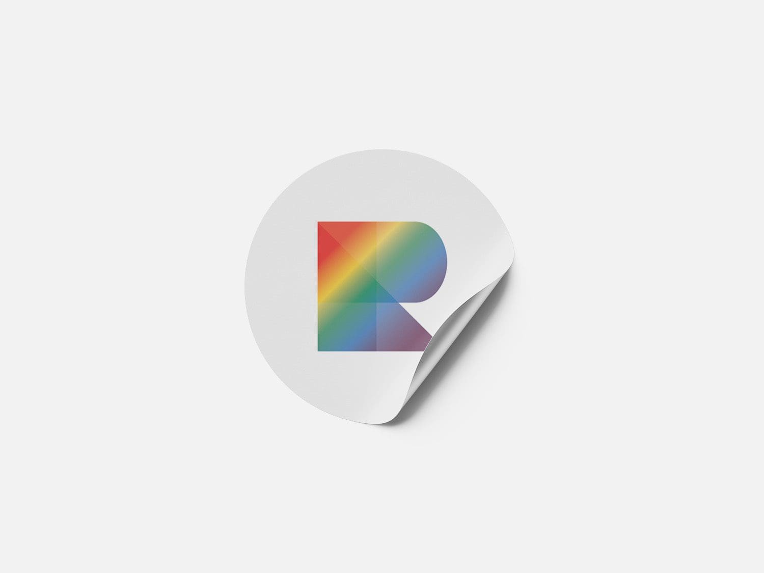 rainbow productions favicon logo shown on a white circle sticker on a white background. The corner of the sticker is curled up as if it has started to peel off the surface